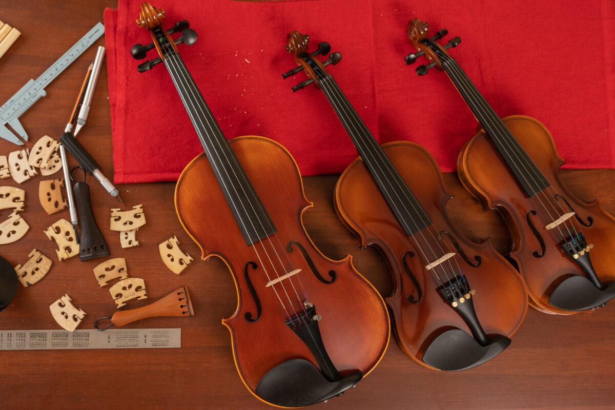Top view of three violins in a workshop with different tools to fix violin rentals