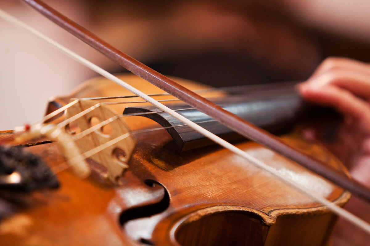 up close photo of someone playing the violin with violin accessories including a bow