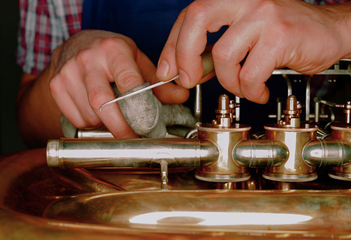 close up of mans hands repairing a brass instrument from instrument repair courses
